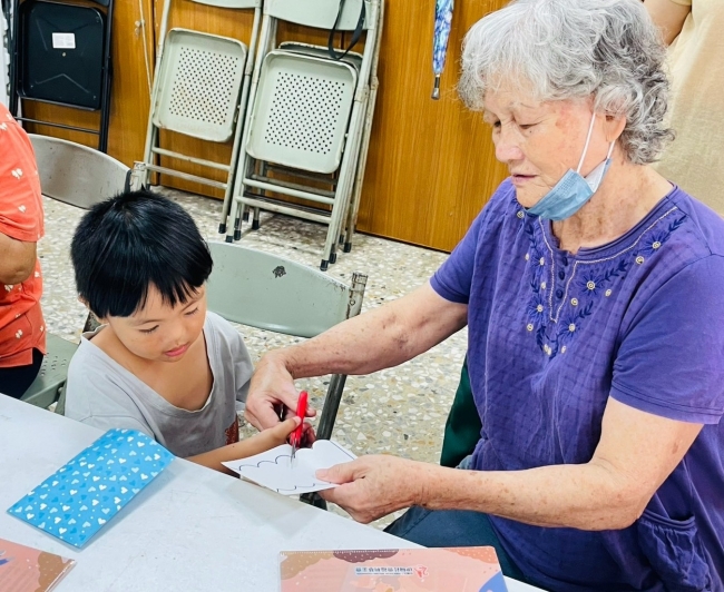区长辈细心协助幼童使用剪刀制作图样,体现社区「老少共融」与互助共学的意涵。