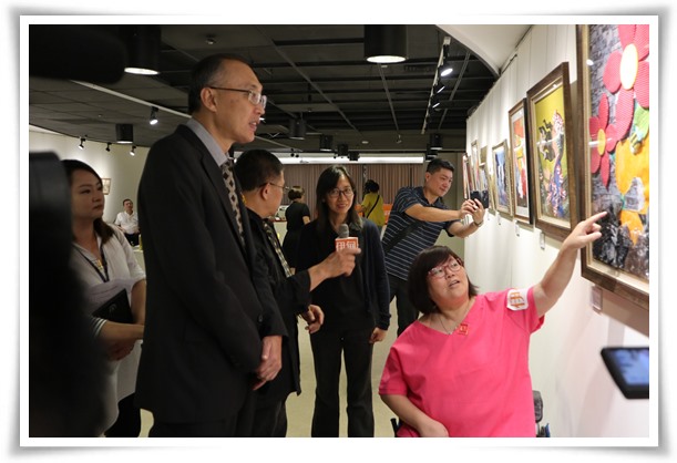 半瘫的伊甸身障艺术家韾文与新北市副市长谢政达介绍拼布作品，展现十足的生命力