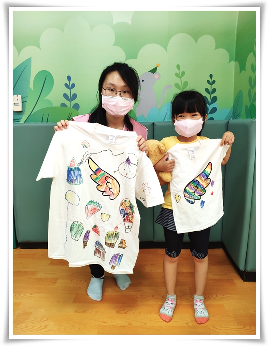 孩子为慢飞天使的翅膀涂上七彩的颜色，自信地展示出自己创作的手绘T-shirt的模样十分可爱！
