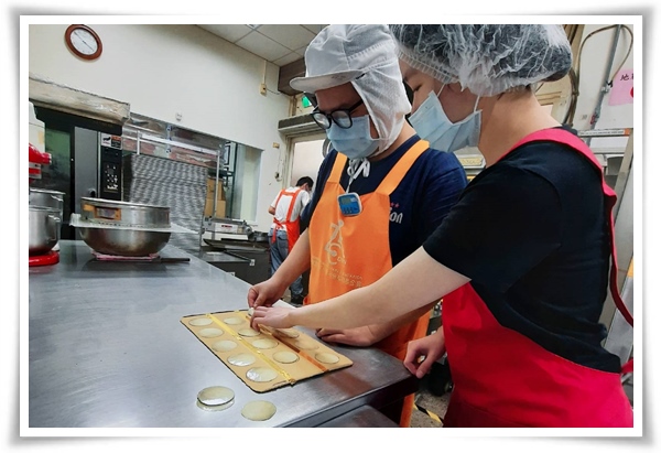 小扬(左)透过伊甸就业服务员的职务再设计，以辅具及图示说明与练习烤饼干时的排盘操作
