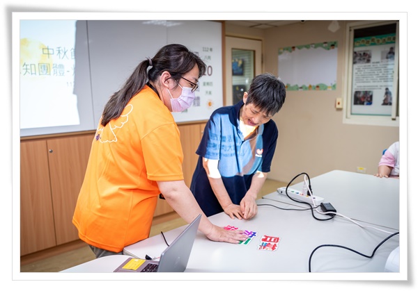 职能治疗师杨沛璇(左)透过认知团体课程搭配自制图卡，帮助智能障碍者反复学习。