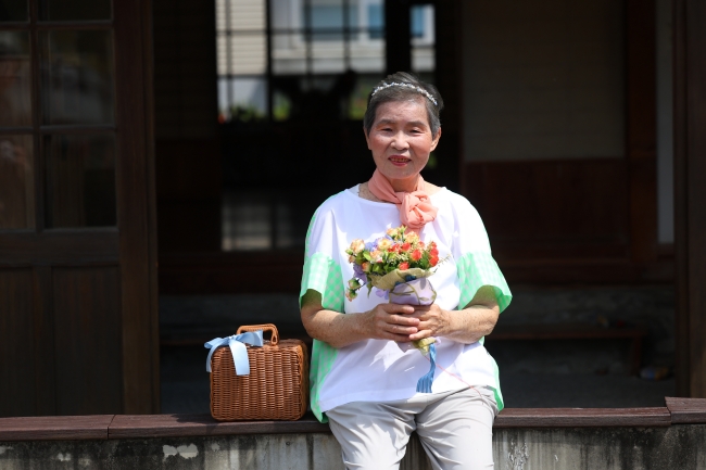 李珠阿嬷拿着花与小篮子等道具,专业摆拍